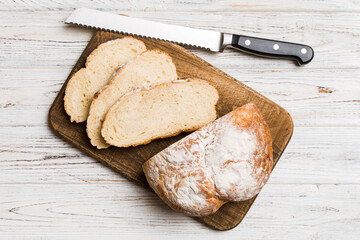 Freshly baked bread cut with knife on a wooden board. top view Sliced bread and knife