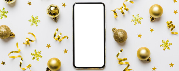 Christmas online shopping from home phone with blank white display top view. smart mobile with copy space on colored background with Christmas decorations balls,. Winter holidays sales background