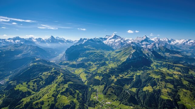 A stunning aerial view of the Swiss Alps in summer, with lush green valleys, snow-capped peaks, and clear blue skies