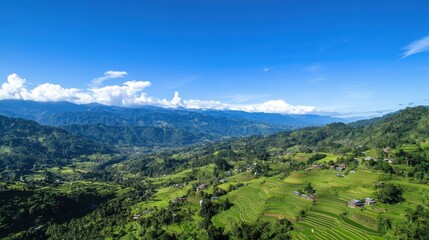Obraz premium Breathtaking landscape showcases lush rice terraces interwoven with village homes, set against a backdrop of majestic mountains and clear skies