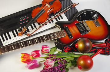 Musical instruments electric guitar, violin and synthesizer, a bouquet of tulips on a light...