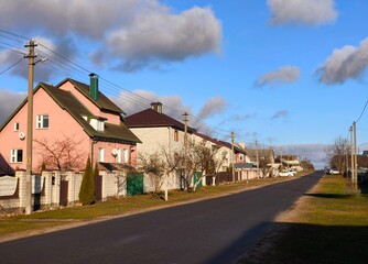 Real estate concept: City street of single-family modern houses against blue sky. A number of private houses in a residential area in Europe.