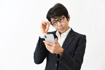 スマホを見る老眼に悩む中高年の女性