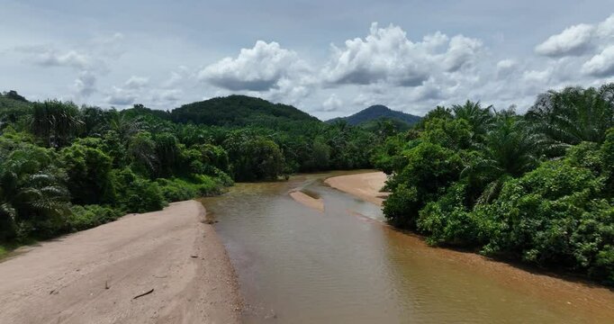 Drone footage of Plai Wha river surrounded by green forest and cloudy sky in Thailand