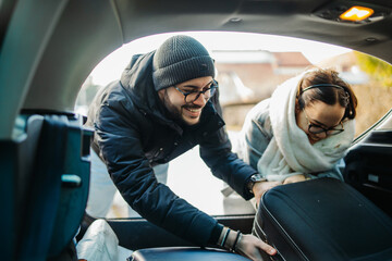 Boyfriend and girlfriend packing suitcases in car preparing to travel	