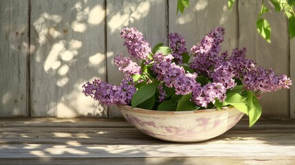 Lilac blossoms displayed in a chipped ceramic bowl, resting on a weathered wooden porch with soft dappled sunlight