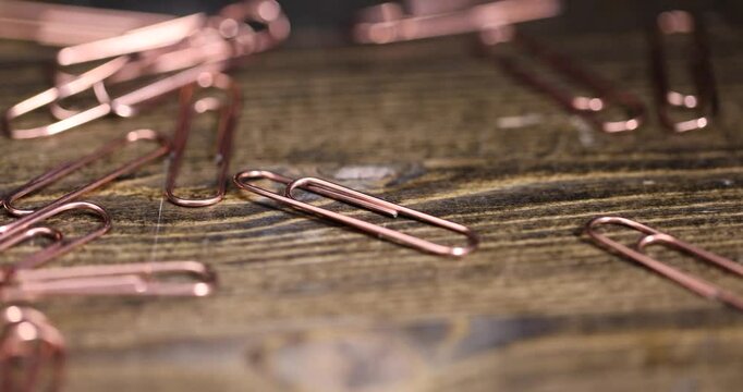 group of copper paper clips for the systematization of documents and paper, large-size copper paper clips close-up on the board