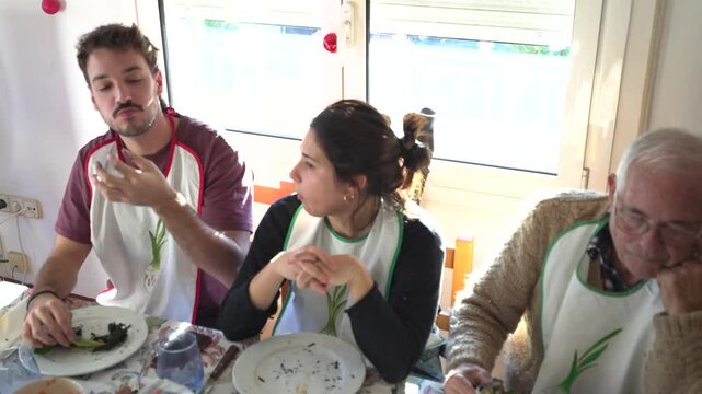 family at the table eating cal&ccedil;ots, very natural video of the meal, couple sharing a bite, with bib in a traditional Catalan meal.