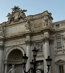 Visitors admire the intricate architecture of the Trevi Fountain in Rome during a sunny afternoon