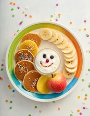 Obraz premium Colorful and funny kids' breakfast with pancakes, yogurt, banana and apple