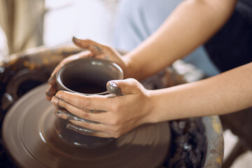 Hands of craftsman artist working on pottery wheel.