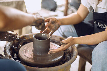 Hands of craftsman artist working on pottery wheel.