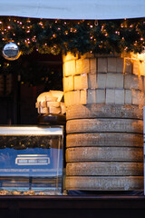 A rustic market stall showcasing large wheels of cheese and smaller packaged portions under warm...