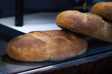 A freshly baked loaf of bread rests on a rustic wooden shelf, exuding warmth and inviting aroma, symbolizing simplicity, tradition, and the art of baking.

