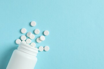 Various pills pouring out of medicine bottle on color background