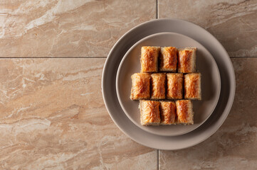 Baklava with walnuts on a beige plate.