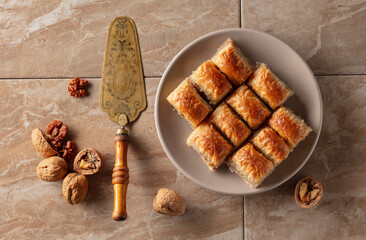 Baklava with walnuts on a beige plate.