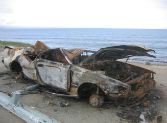 A burnt-out car on the seashore.
The island of a completely burnt-out car stands on the seashore....