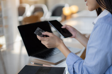 Beautiful Asian girl is happy and enjoys shopping online at coffee shop.