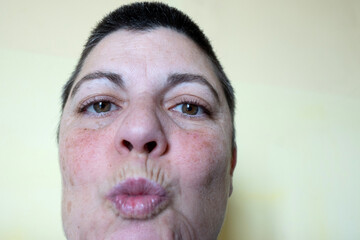 Fototapeta premium close-up portrait of binary woman with short hair kissing the camera, detail of face and eyes.