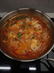 Delicious tomato sauce simmering with grated cheese and herbs in a pan