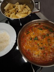 Cooking rigatoni pasta with tomato sauce and grated cheese in prague