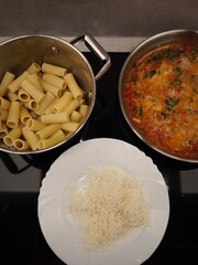 Preparing rigatoni pasta with tomato sauce and grated cheese in prague