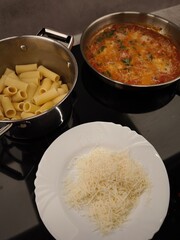 Chef preparing rigatoni pasta with tomato sauce and grated cheese in prague