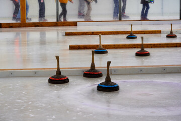 Wooden curling stones with handles are scattered across an icy surface during a game