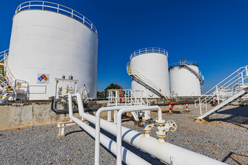 Obraz premium Crude Oil Industry, White Storage Fuel Gas Container Tanks in Petroleum Refinery Industrial Factory area against