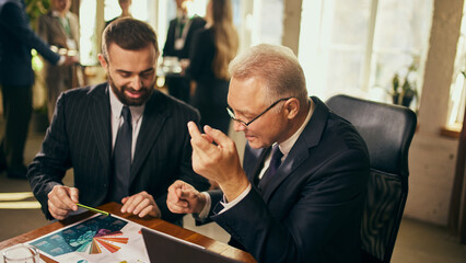 Two business professionals analyzing colorful data chart during meeting in bright modern office....