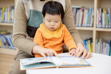 어린이 도서관에서 엄마와 함께 책을 보는 아기