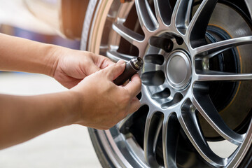 Car service, maintenance basic concept, Close up hand a man removing the rear wheel nuts of a car and hold in hand check the completeness of the parts, Brake, Flat tire, Brake Pad thickness check