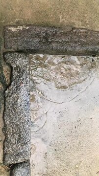 Raindrops create ripples on the stone-paved ground of a Korean traditional seowon, capturing a serene and timeless atmosphere.