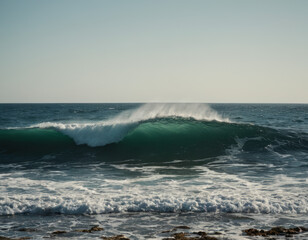 Fototapeta premium Waves crashing onto the shore, their foam sparkling in the light.