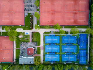 Aerial view of orange tennis courts and blue colored padel courts