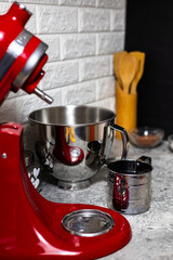 Professional red mixer on the kitchen table surrounded by ingredients. 