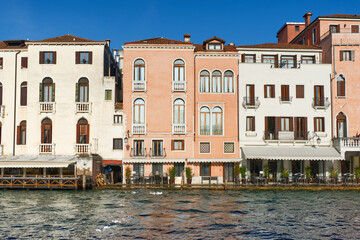Naklejka premium The image captures colorful Venetian buildings lining a serene canal in Venice, Italy, showcasing its charming architecture, balconies, and reflections on the tranquil waters.