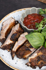 A plate of fried pork ribs with sauce and greens. Delicious meat dish