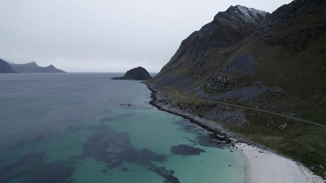 This aerial video captures the stunning beauty of Haukland Beach, located on the Lofoten Islands in Norway. The beach is known for its crystal-clear turquoise waters, pristine white sands, and dramati