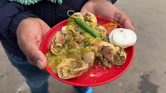 Close up shot of Litti chokha served in a red plate.