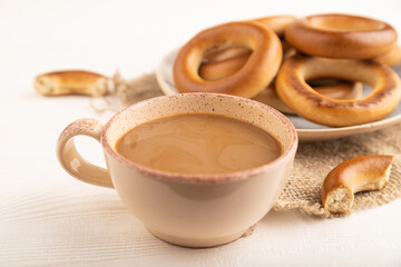 Homemade Ring Bagel with cup of coffee on white wooden background, side view, selective focus.