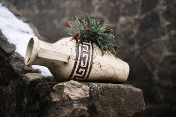 Antique decor. The broken Greek amphora, which grows flowers in the ancient monastery. Beautiful flower bed in the form of an old amphora vase. Street decor items. Decorative ceramic pots. Winter.