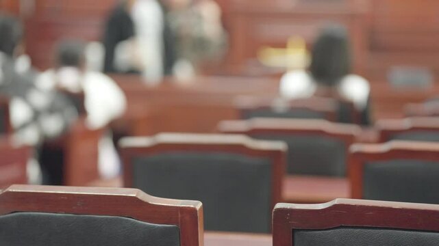 A row of wooden chairs with black seats and backs. The chairs are empty and the room is empty