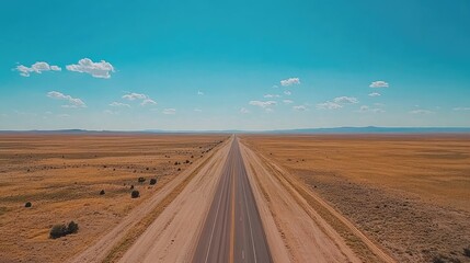 A straight highway cutting through a vast desert landscape under a bright blue sky with a few scattered clouds, showcasing endless freedom and adventure