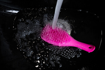 Pink hairbrush with water flowing