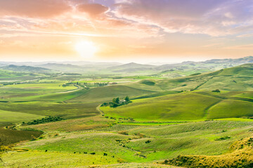 Fototapeta premium green spring season landscape of beautiful grassland hills in countryside with villages and mountains under scenic cloudy sky