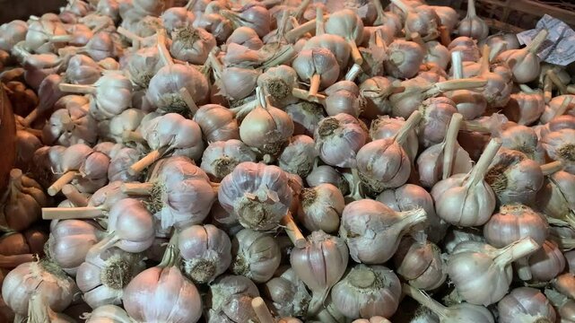 A pile of fresh garlic bulbs stacked in a market display.
