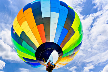 Obraz premium Colorful hot air balloon flying over blue sky with white clouds 