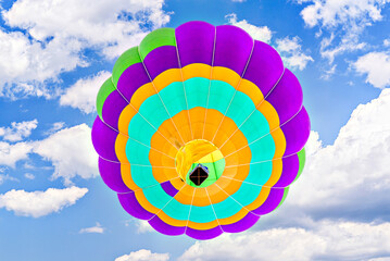 Colorful hot air balloon flying over blue sky with white clouds	